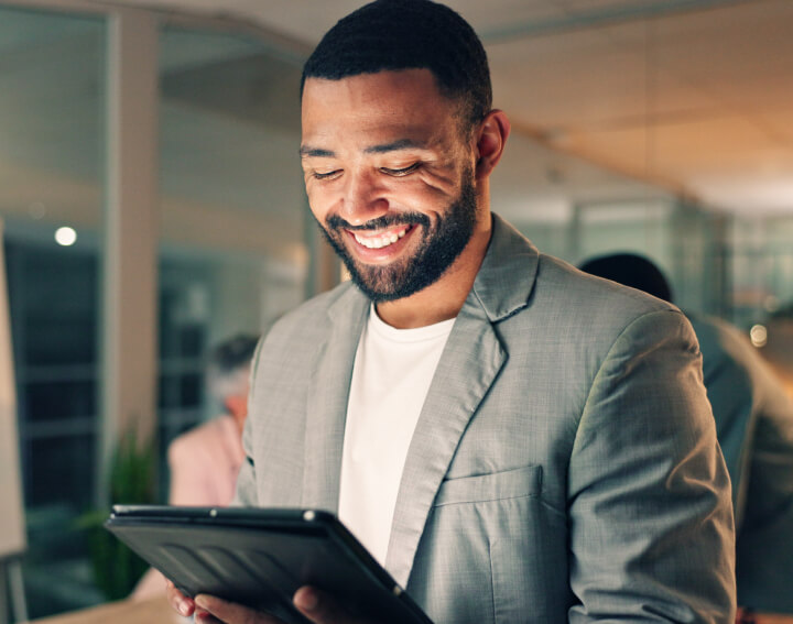 Homem olhando para um tablet e sorrindo